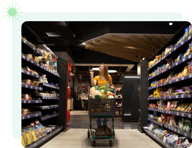 A woman is seen shopping for groceries in a well-stocked store aisle, selecting items from the shelves.